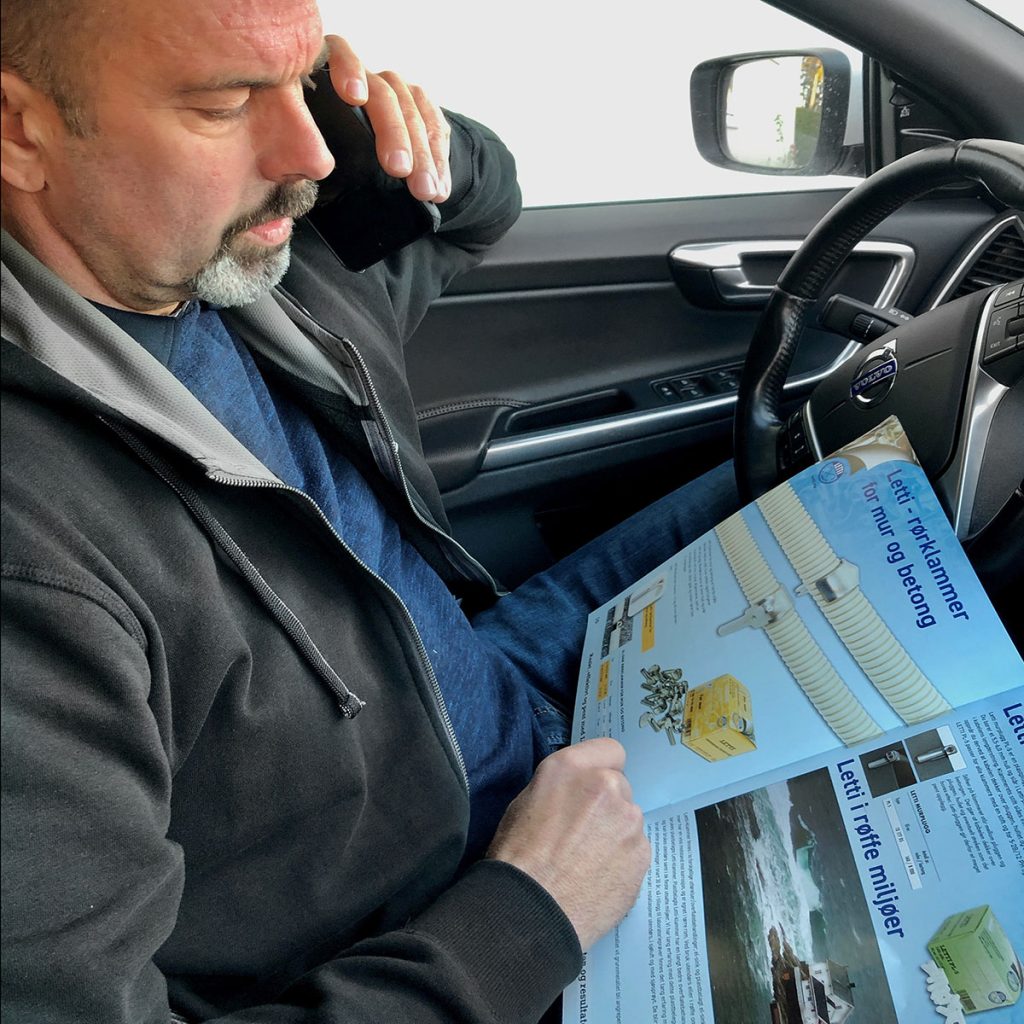 Mann i bil som snakker i telefon og har en brosjyre om lettiklammer